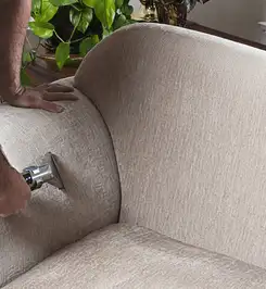 Professional upholstery cleaner deep-cleaning a fabric sofa with a handheld extraction tool and hose Seattle, WA.